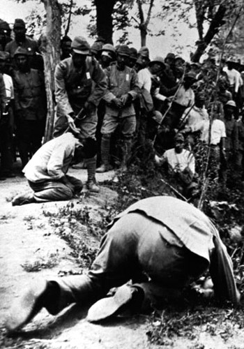 Żołnierz japoński pokazuje jak ściąć głowę więźniowi