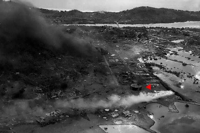 Zniszczenia i pożary na wyspie Dublon powstałe w czasie ataków amerykańskich samolotów. Czerwona strzałka wskazuje na, jeszcze nie zniszczony, duży zbiornik paliwa